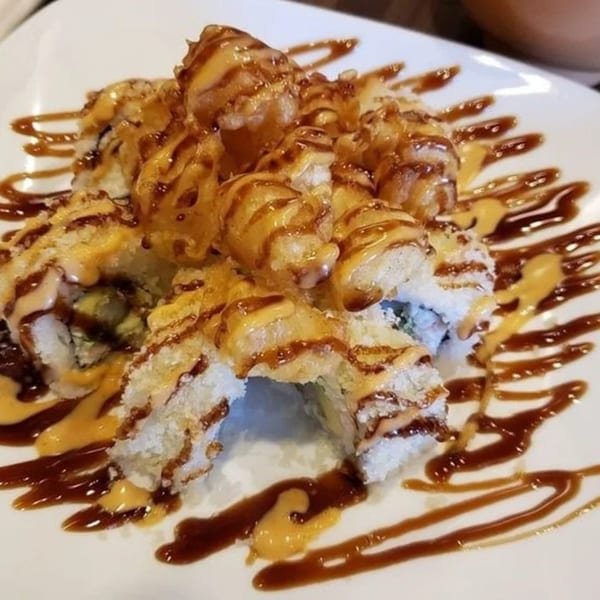Chopstix 2's fried sushi rolls, drizzled with dark and light sauces, on a white plate.