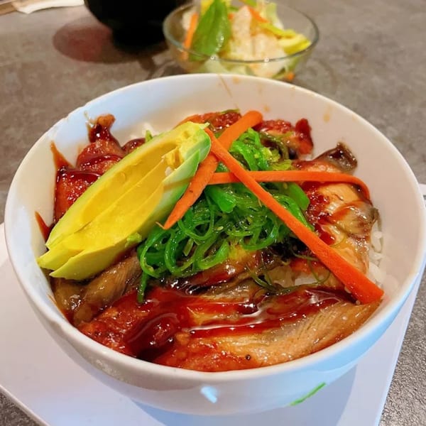 Chopstix 2 sushi bowl with eel, avocado, seaweed salad, and carrots, with a side salad.